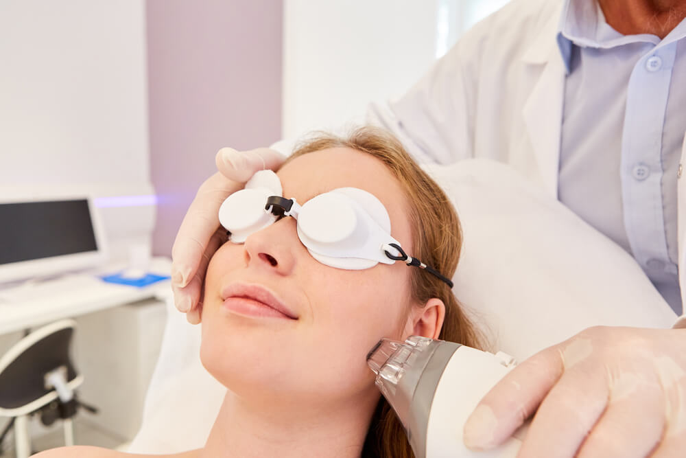 Kobieta w specjalistycznych białych okularach ochronnych podczas zabiegu laserowego w klinice medycznej